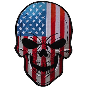 May include: Embroidered patch featuring a skull design with the American flag incorporated. The top half of the skull displays the blue field with white stars, while the lower half features red and white stripes. The skull has black eye sockets and a menacing grin.