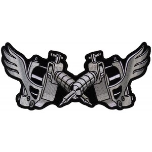 May include: A black and white embroidered patch featuring two crossed tattoo machines with wings. The machines are silver and the wings are white.