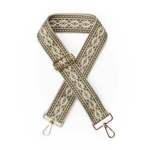 May include: A decorative bag strap with a geometric pattern in shades of green, beige, and brown. The strap has gold-colored metal hardware, including a buckle and two swivel clasps. The strap is approximately 1.5 inches wide.