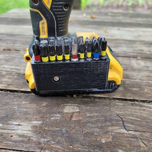 May include: A black plastic holder with a variety of screwdriver bits attached to a yellow and black power drill.