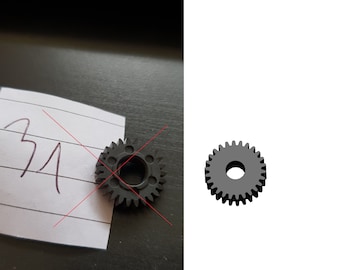 May include: A black plastic gear with a central hole. The gear has 20 teeth.