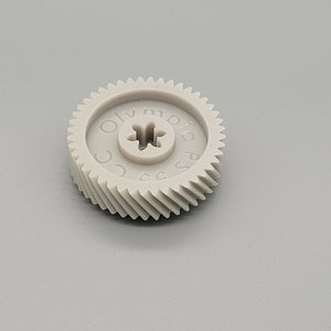 May include: A gray plastic gear with the text "Olympia Plus" printed on the side.