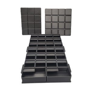 Peut inclure: Plateaux et panneaux de rangement en plastique noir. Les plateaux sont disposés en gradins, avec de multiples petits compartiments. Deux panneaux carrés avec un motif quadrillé sont derrière les plateaux. Les articles sont probablement destinés à organiser de petits objets.
