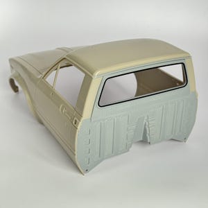 以下が含まれることがあります： ベージュとライトグレーのツートンカラーのモデルトラックキャブ。 キャブは、屋根、フロントガラスフレーム、リアウィンドウ開口部を備えています。 リアセクションには垂直パネルの詳細があります。 このモデルは、愛好家やコレクター向けに設計されています。