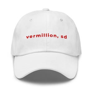 Peut inclure: Casquette de baseball blanche avec le texte rouge brodé "vermillion, sd". La casquette a une visière incurvée et une sangle réglable. Un accessoire décontracté.