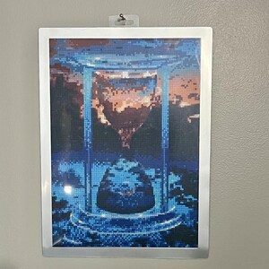 May include: A framed diamond painting depicting an hourglass with a blue and orange sky in the background.