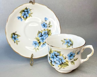 May include: A white teacup and saucer with a blue and yellow floral pattern. The cup and saucer have a gold trim.