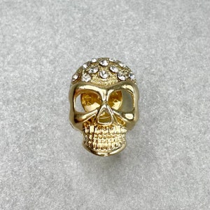 May include: Gold-tone skull pin with clear rhinestones.