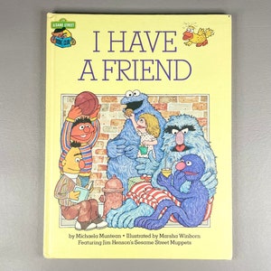 Pode incluir: Um livro amarelo com o título "Eu tenho um amigo" com personagens da Vila Sésamo como Cookie Monster, Big Bird e Elmo. O livro faz parte do Sesame Street Book Club.