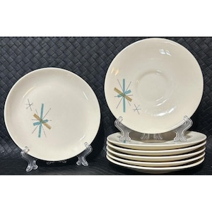 Op de afbeelding: Set van zes witte keramische dinerborden met een mid-century modern design met een gestileerd sterburst-patroon in tinten teal, goud en wit.