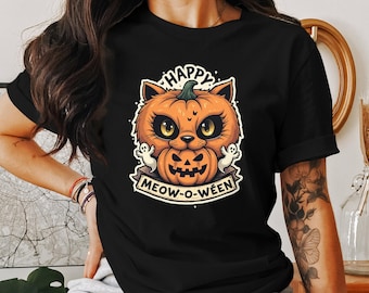 May include: Black t-shirt featuring a graphic of a cat wearing a pumpkin on its head. The text "Happy Meow-O-Ween" is printed below the cat.