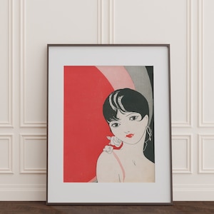 May include: A framed print of a woman with black hair and red lips. She is wearing a white flower behind her ear and is looking to the left. The background is a red, pink, and black abstract design.
