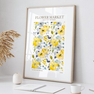 May include: Framed art print featuring a watercolor floral pattern in yellow, gray, and blue. The print includes the text "FLOWER MARKET COLLECTION BOTANIQUE" and "GALLERIE D'ART MODERN London". The artwork is displayed on a white surface.