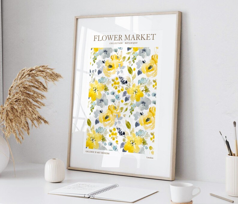 May include: Framed art print featuring a watercolor floral pattern in yellow, gray, and blue. The print includes the text "FLOWER MARKET COLLECTION BOTANIQUE" and "GALLERIE D'ART MODERN London". The artwork is displayed on a white surface.