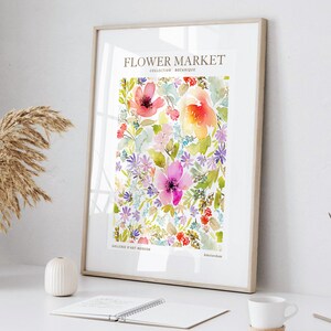 May include: A framed watercolor print featuring a vibrant floral design. The artwork showcases a variety of colorful flowers in shades of pink, red, yellow, and purple, with green foliage. The print includes the text "Flower Market" and "Collection Botanique".