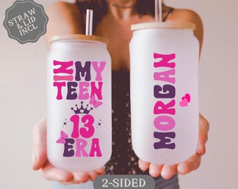 May include: Two pink and purple personalized tumblers with lids and straws. One tumbler says "My Teen 13 Era" and the other says "Morgan".