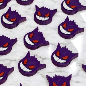 May include: Multiple purple and white 3D printed Ghost Pokemon figures with red eyes.