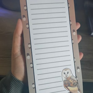 May include: A brown and white notepad with a white owl illustration. The notepad has a dotted pattern on the edges and lined paper inside.