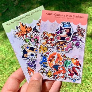 Pu&ograve; includere: Due confezioni di adesivi Kanto Classics Mini. Una confezione &egrave; verde con la scritta "Ship Form I Set of 25". L'altra confezione &egrave; rosa con la scritta "Regular Form I Set of 25". Ogni confezione contiene adesivi di cartoni animati colorati.