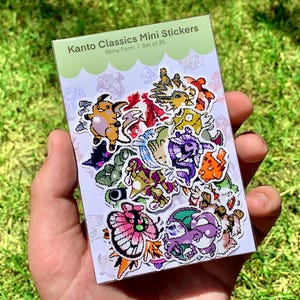 Pu&ograve; includere: Un pacchetto di mini adesivi Kanto Classics, Shiny Form, Set di 25. Gli adesivi presentano vari personaggi dei cartoni animati colorati. Il pacchetto &egrave; tenuto in mano su uno sfondo di erba verde.