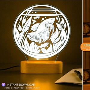 May include: A white 3D printed night light featuring a design of a betta fish in a fish tank. The night light sits on a wooden base and emits a warm white glow.