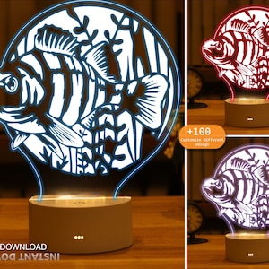 May include: A white 3D printed night light shaped like a fish with a blue glow. The light is on a white base with three black dots. The image also shows a red and purple version of the light.