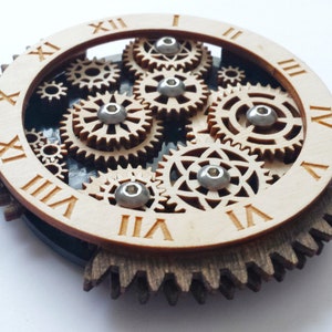 Può includere: Un quadrante di orologio in legno con numeri romani e un meccanismo di ingranaggi dettagliato al centro. Gli ingranaggi sono in legno e hanno una finitura naturale.