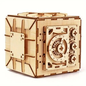May include: A wooden model of a safe with a detailed, intricate design. The safe has a large dial with gears and a handle. The safe is made of light wood and has a natural finish.