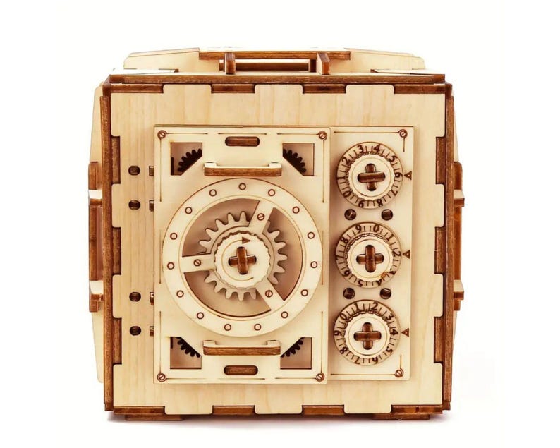 May include: A wooden model of a safe with a combination lock and a working dial. The safe is made of light brown wood and has a realistic design.
