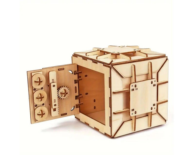 May include: A wooden model of a safe with a working door and a combination lock. The safe is made of light brown wood and has a detailed design.
