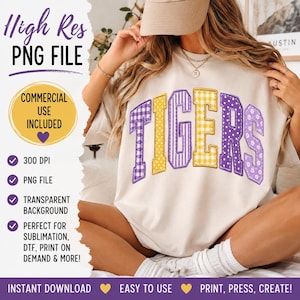 Puede incluir: Una camiseta beige con la palabra TIGERS en letras grandes y arqueadas de estilo bloque. Cada letra tiene un patrón único, incluyendo cuadros vichy morados, lunares amarillos, rayas moradas, cuadros vichy amarillos, lunares morados y flores.