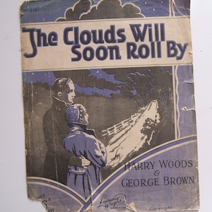 Peut inclure: Une couverture de partition de musique vintage aux couleurs bleu et blanc. Le titre est "The Clouds Will Soon Roll By" par Harry Woods & George Brown. La couverture représente un couple debout dans un champ avec un ciel nuageux en arrière-plan.