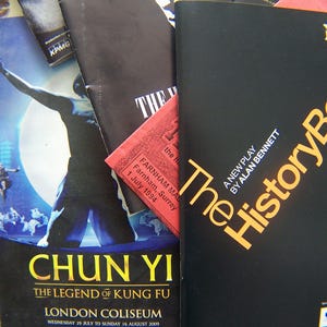May include: A collection of theatre programmes and promotional leaflets. A black programme for "The History Boys" is visible, alongside a blue one advertising "Chun Yi: The Legend of Kung Fu" at the London Coliseum.