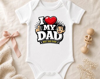 May include: A white short-sleeved baby bodysuit featuring a graphic print that says I LOVE MY DAD with a red heart, a cartoon character giving a thumbs up, and the text BEST DAD EVER! in yellow on a black banner with white stars.