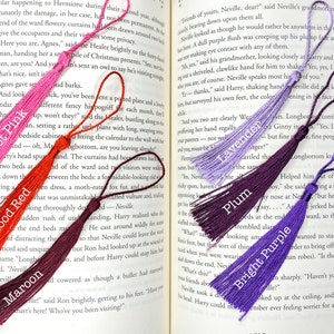 Tassels of varying colors are laid out on the open pages of a book. The tassels are labeled by color.