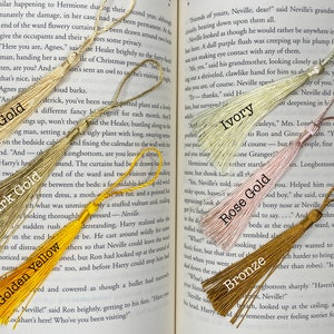 Tassels of varying colors are laid out on the open pages of a book. The tassels are labeled by color.
