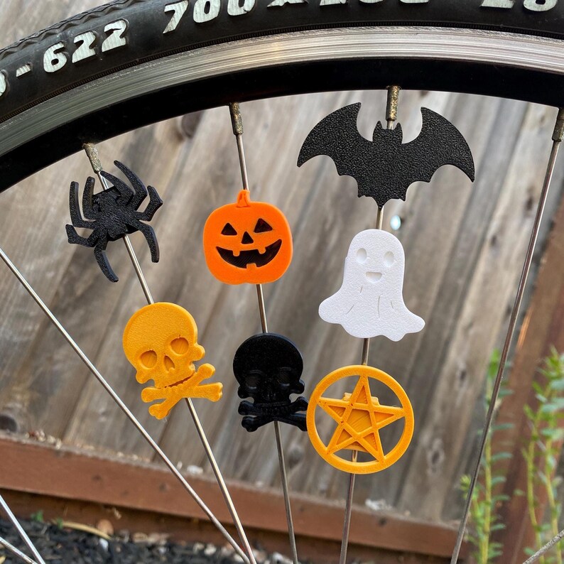 bat, spider, skull, ghost, and pentagram bike decorations on a bicycle wheel