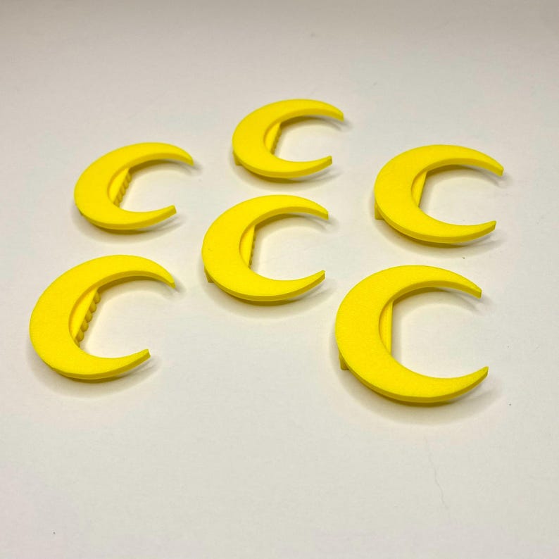 May include: Six bright yellow crescent moon-shaped objects. Each moon has a curved design with a straight edge on the inside. The objects are evenly spaced against a white background. The moons are likely decorative or craft elements.
