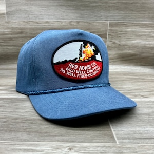 May include: A blue denim trucker hat with a red, white, and black embroidered patch that reads "Red Adair Co. Wild Well Control Oil Well Fires-Blowouts".