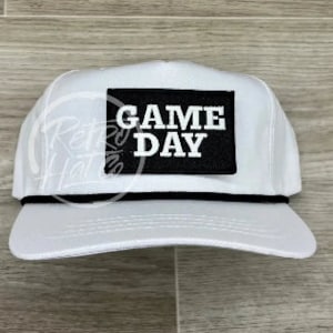 May include: White baseball cap with a black patch that says "GAME DAY" in white letters.