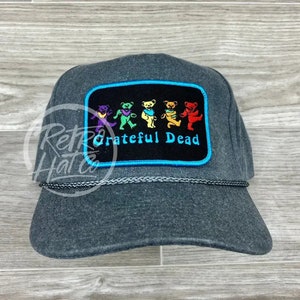 May include: A gray trucker hat with a black patch featuring five dancing bears and the text "Grateful Dead" in white. The patch has a blue border.