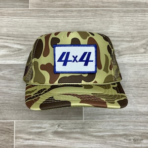 Puede incluir: Gorra de camionero de camuflaje con un parche azul y blanco que dice "4x4".