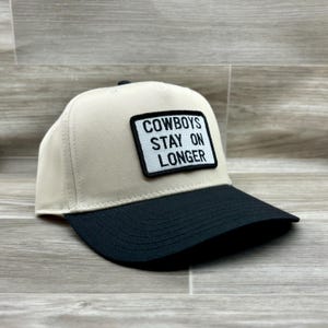 May include: A beige and black baseball cap with a black patch that reads "COWBOYS STAY ON LONGER".