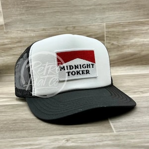 May include: A white and black trucker hat with a red and white patch that says "MIDNIGHT TOKER".