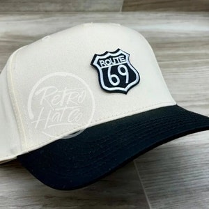 May include: A white and black baseball cap with a black and white Route 69 patch on the front.