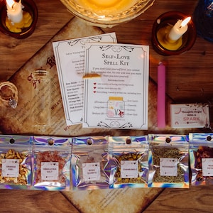 May include: Self-love spell kit with a pink candle, a small jar of herbs, and six small bags of ingredients, including rose petals, orange peel, Himalayan salt, rose quartz, chamomile, and rosemary. The kit includes instructions with affirmations and a pink soap bar that says "Thoughts Begin with a Spark".