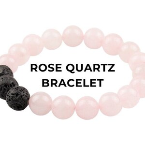 Puede incluir: Un brazalete de cuarzo rosa de color rosa con cuentas de lava negra. El brazalete tiene el texto "ROSE QUARTZ BRACELET".
