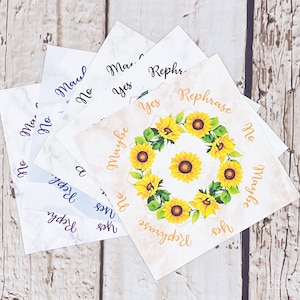 May include: A set of eight white cards with different phrases written on them. The phrases include "Yes", "No", "Maybe", "Rephrase", and "Maul". The cards are arranged in a circle with a sunflower design in the center.