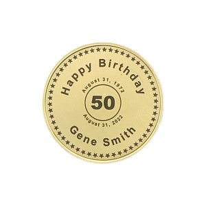 May include: Gold-colored round coin with a black inscription that reads "Happy Birthday" with a star border. Inside the border is a circle with the text "August 31, 1972" and "August 31, 2022" and the number "50" in the center. Below the circle is the text "Gene Smith".