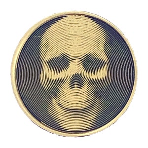 May include: A gold-colored circular coin with a black and gold skull design. The skull is created using concentric circles.